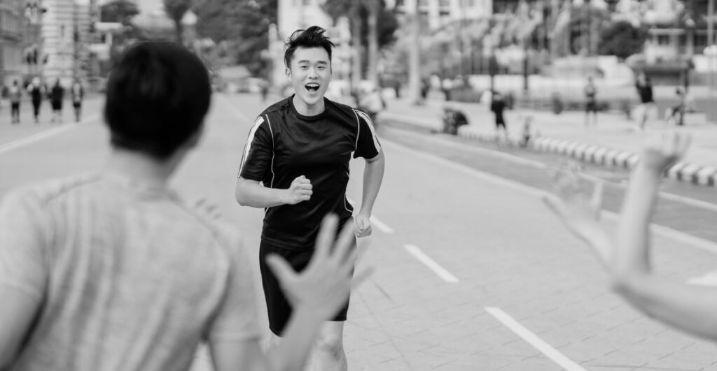 A young runner, smiling, approaches a small group of spectators with hands extended to celebrate
