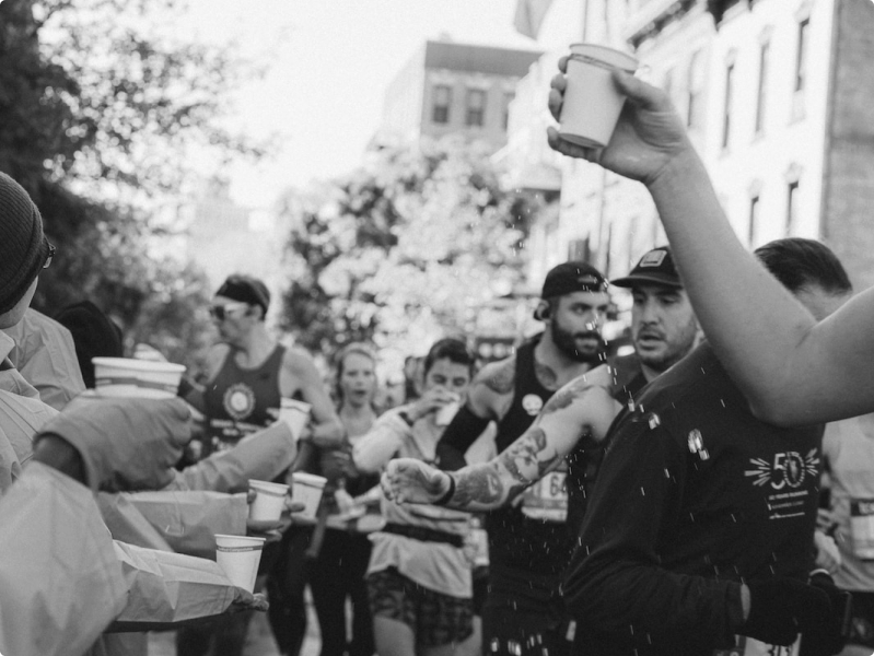 Black and white photos of runners in a line for cups of water during a race.