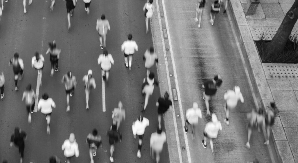 A large group of runners move in unison through the city's streets.
