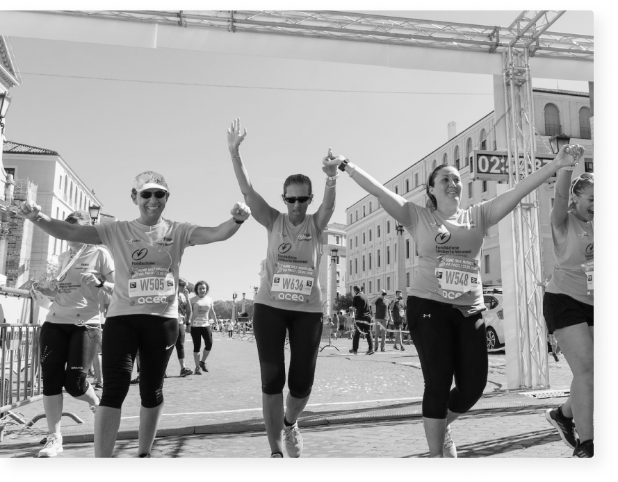 A trio of female runners hold their raises hands as they complete a race.